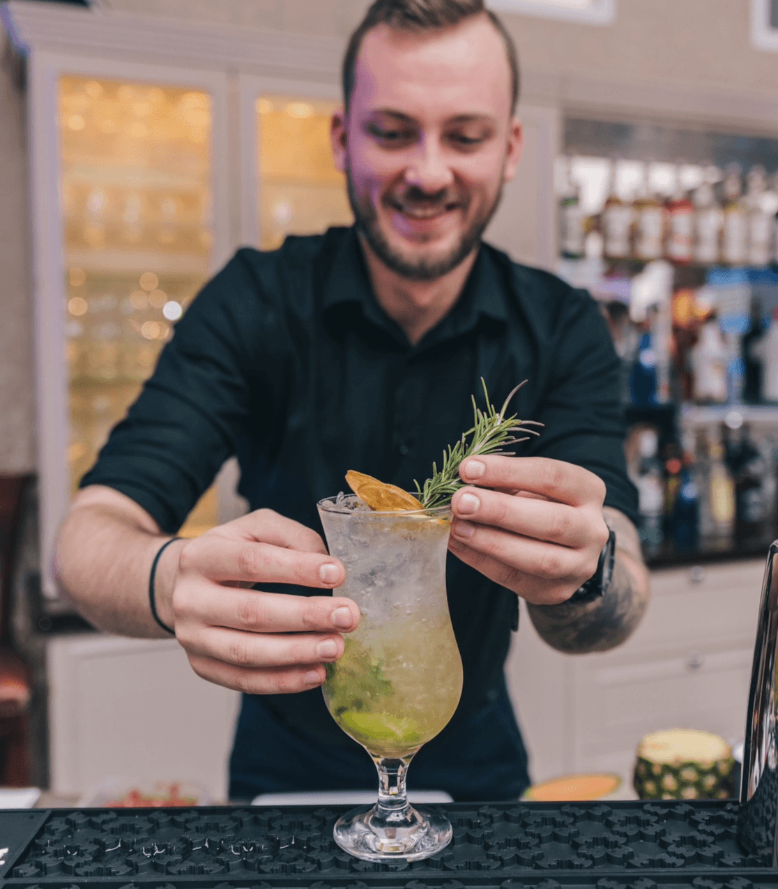 Zdjęcie przedstawia barmana, przygotowującego drink